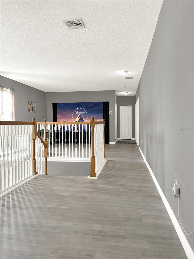 hallway with hardwood / wood-style floors and a textured ceiling