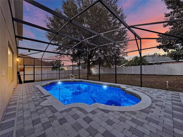 pool at dusk featuring glass enclosure and a patio area