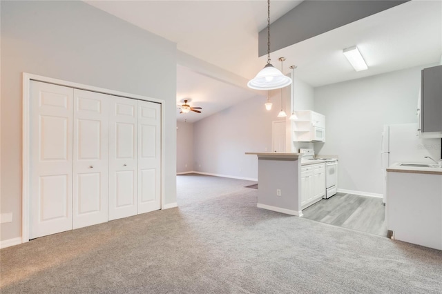 kitchen featuring white appliances, white cabinetry, light carpet, and pendant lighting