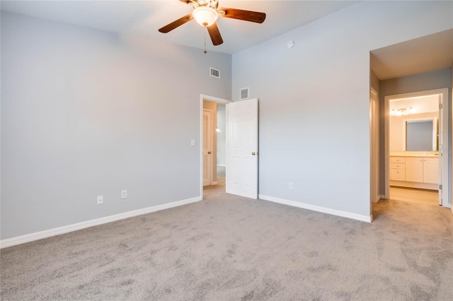 unfurnished bedroom featuring connected bathroom, light colored carpet, and ceiling fan