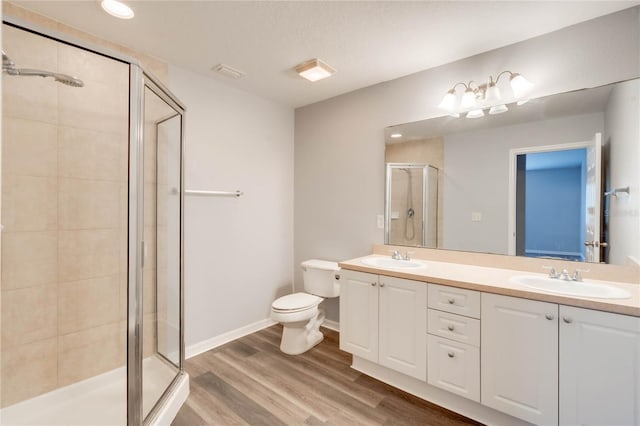 bathroom featuring toilet, vanity, an enclosed shower, and hardwood / wood-style floors