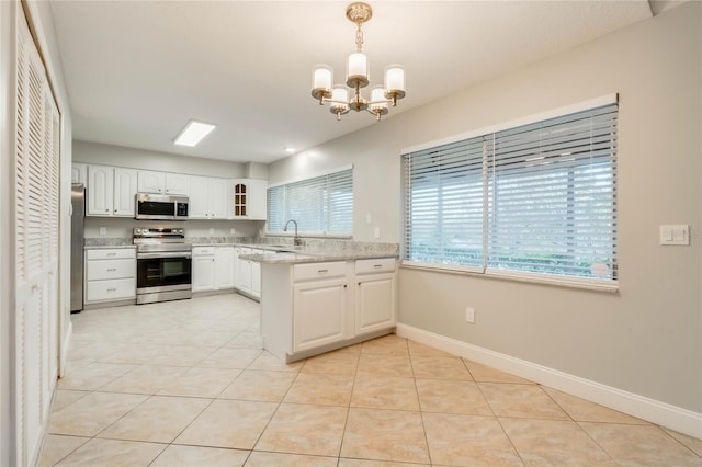 kitchen with pendant lighting, white cabinets, light stone counters, and stainless steel appliances