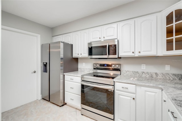 kitchen featuring stainless steel appliances, light tile patterned flooring, white cabinetry, and light stone counters