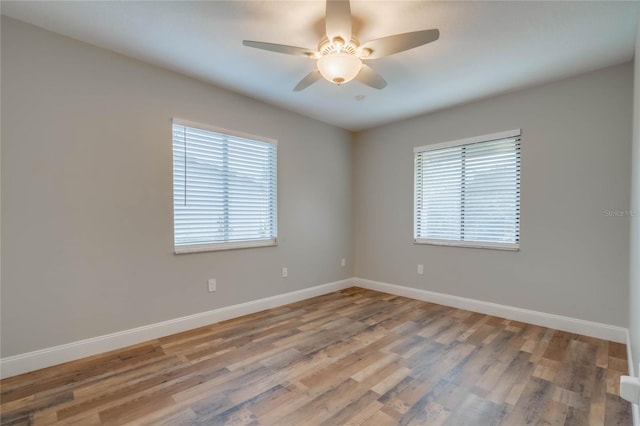 empty room with wood-type flooring, a healthy amount of sunlight, and ceiling fan