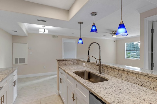 kitchen with white cabinets, sink, a tray ceiling, decorative light fixtures, and light stone counters