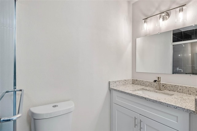 bathroom featuring vanity, a shower with shower door, and toilet