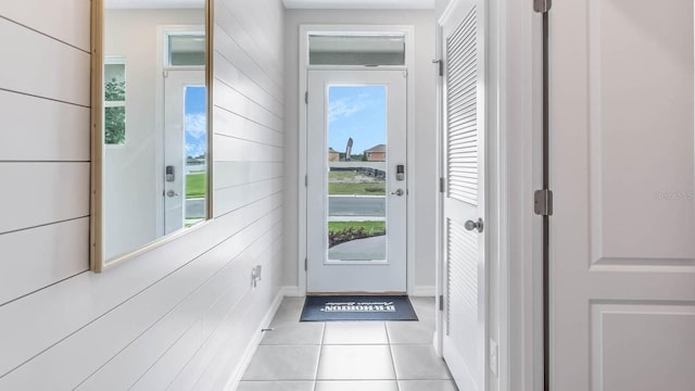 entryway featuring wood walls, light tile patterned flooring, and a healthy amount of sunlight