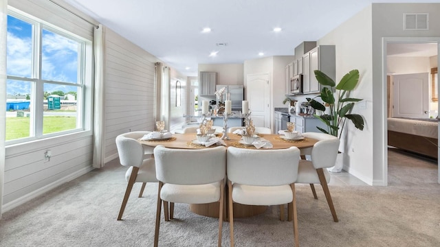 carpeted dining room with wooden walls and plenty of natural light