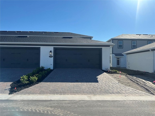 view of front of home with a garage, decorative driveway, and stucco siding