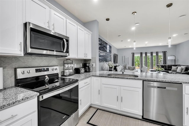 kitchen with white cabinets, stainless steel appliances, sink, and decorative light fixtures