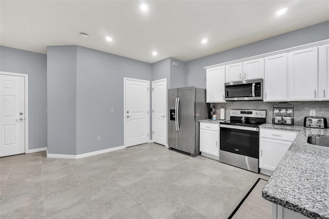 kitchen with light stone counters, appliances with stainless steel finishes, light tile patterned floors, decorative backsplash, and white cabinets