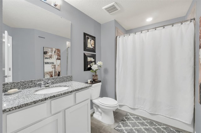 bathroom with a textured ceiling, vanity, tile patterned floors, and toilet