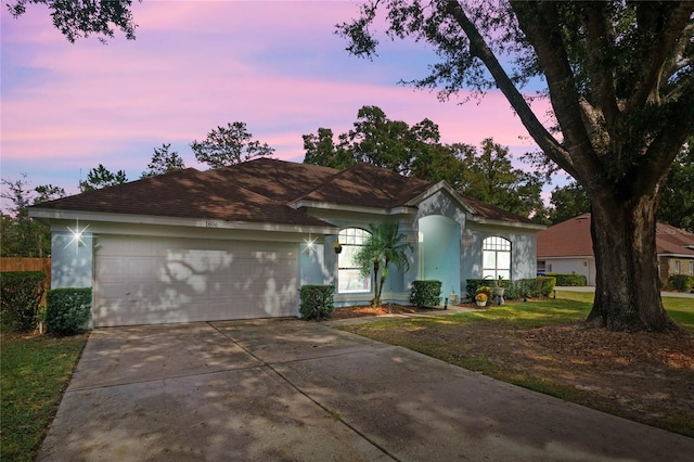 ranch-style home featuring a garage and a lawn