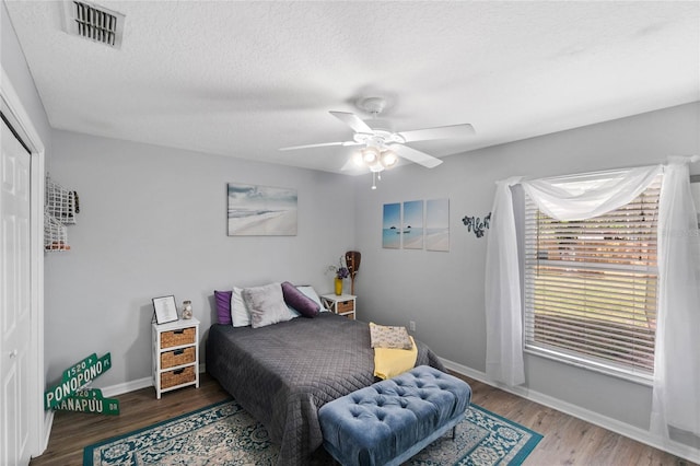 bedroom with ceiling fan, a closet, hardwood / wood-style floors, and a textured ceiling