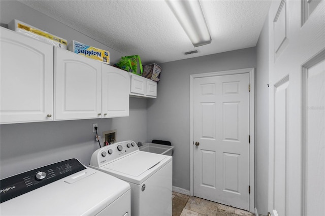 washroom with cabinets, washer and dryer, and a textured ceiling