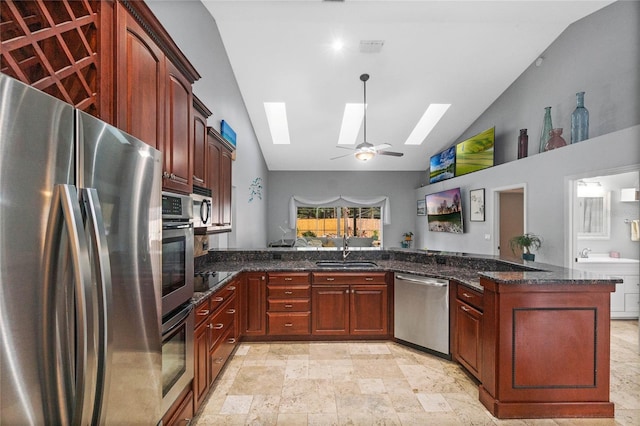 kitchen with sink, ceiling fan, dark stone countertops, stainless steel appliances, and kitchen peninsula