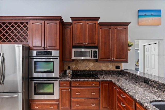 kitchen featuring stainless steel appliances, tasteful backsplash, and dark stone countertops