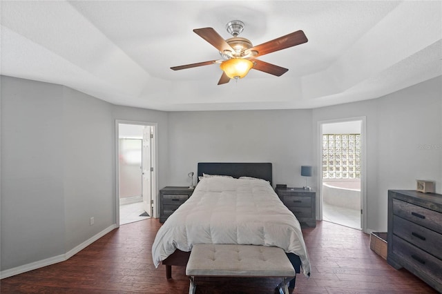 bedroom with dark hardwood / wood-style floors, ensuite bath, and a raised ceiling