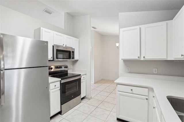 kitchen featuring white cabinets, appliances with stainless steel finishes, and light tile patterned floors