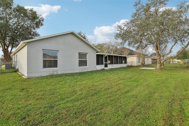 rear view of house featuring a sunroom and a yard