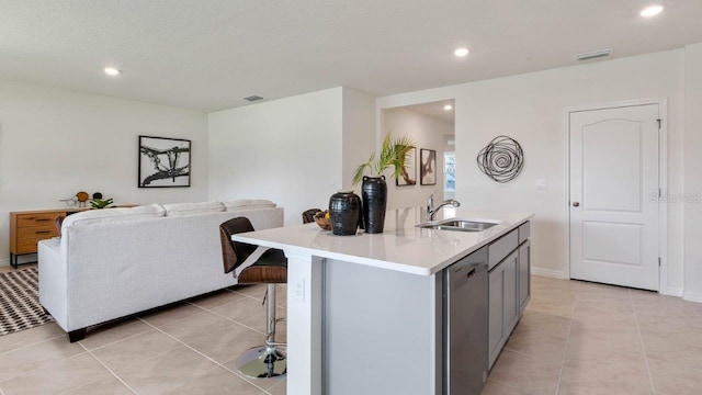 kitchen with sink, a breakfast bar, light tile patterned floors, stainless steel dishwasher, and gray cabinets