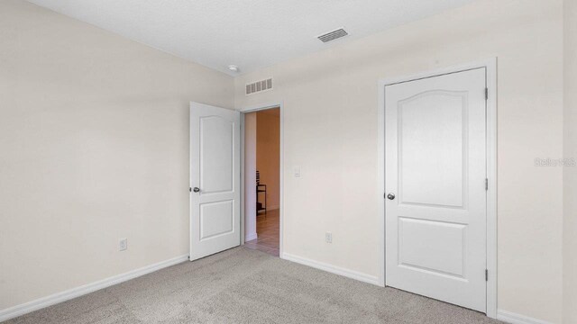 unfurnished bedroom with a textured ceiling and light carpet