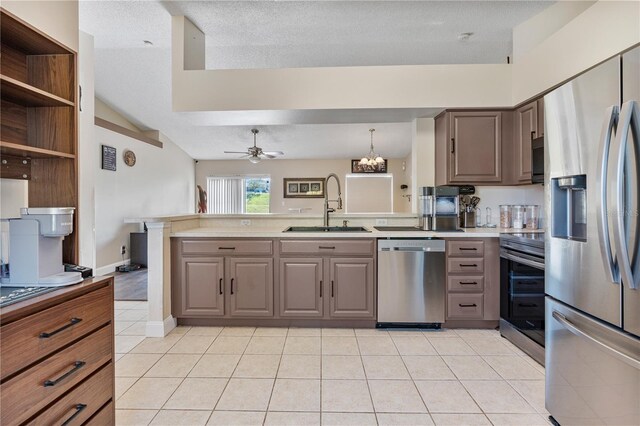 kitchen featuring sink, appliances with stainless steel finishes, a textured ceiling, light tile patterned floors, and vaulted ceiling