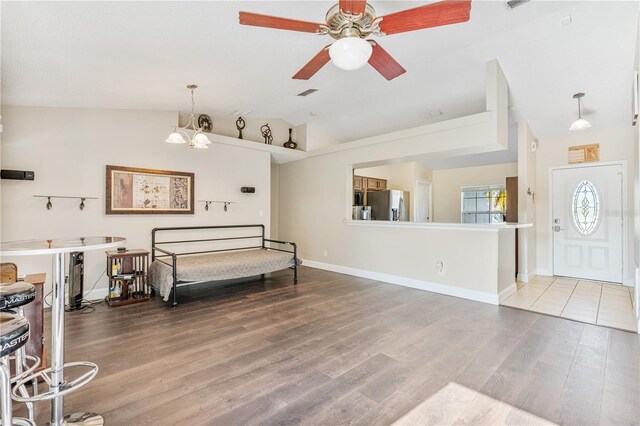 bedroom featuring stainless steel refrigerator with ice dispenser, lofted ceiling, hardwood / wood-style floors, and a notable chandelier