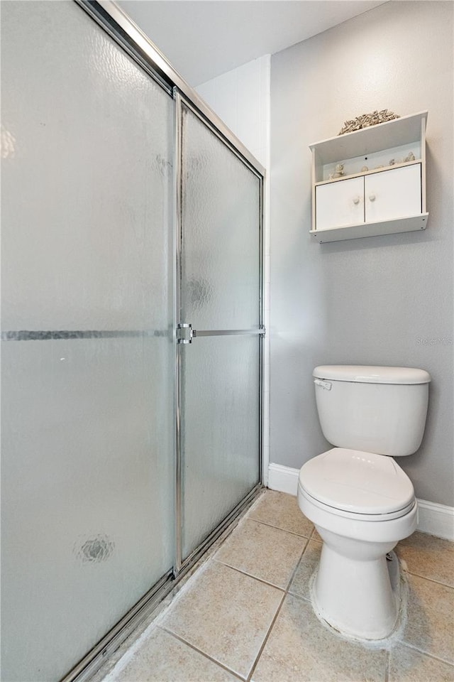 bathroom featuring toilet, an enclosed shower, and tile patterned floors