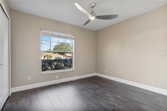 empty room with dark wood-type flooring, ceiling fan, and a textured ceiling