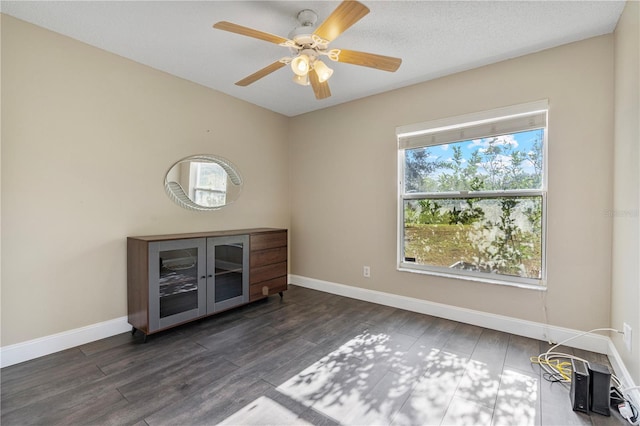 empty room featuring dark wood-type flooring, ceiling fan, and plenty of natural light