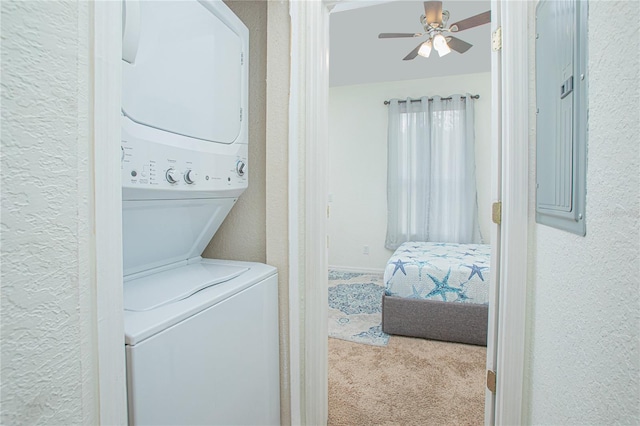 laundry area with stacked washer / dryer, light carpet, and ceiling fan