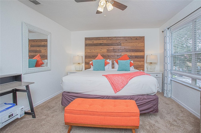 carpeted bedroom featuring ceiling fan and a textured ceiling