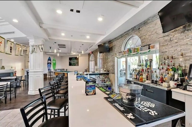 bar with tile patterned floors, beam ceiling, and ornate columns