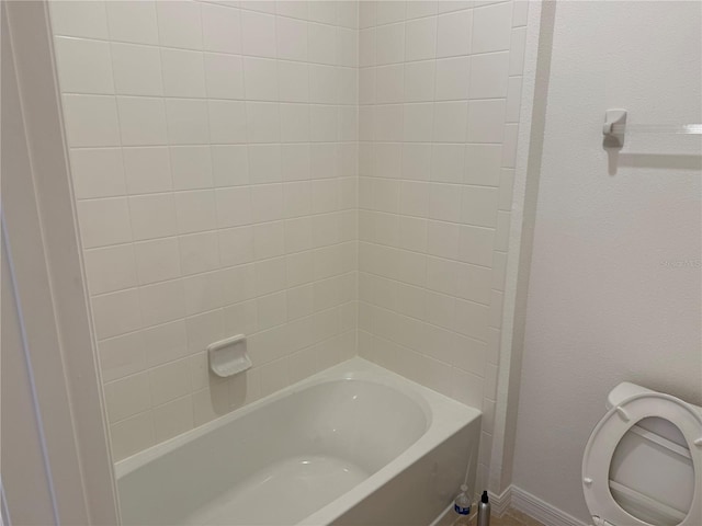 bathroom featuring tiled shower / bath combo and toilet