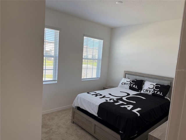 carpeted bedroom featuring a textured ceiling and multiple windows