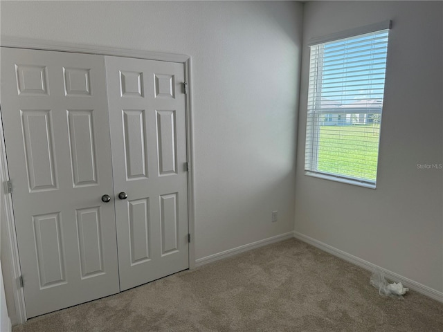 unfurnished bedroom featuring light carpet and a closet