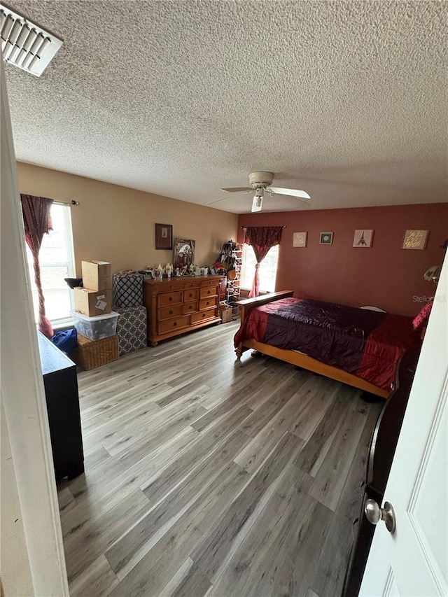 bedroom featuring ceiling fan, light wood-type flooring, and multiple windows