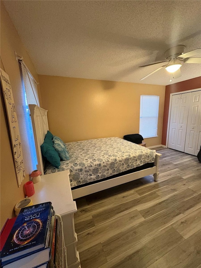 bedroom with ceiling fan, wood-type flooring, a textured ceiling, and a closet