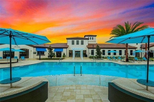 pool at dusk featuring a patio area