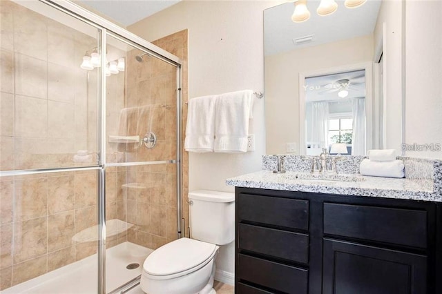 bathroom with toilet, vanity, ceiling fan, and a shower with shower door