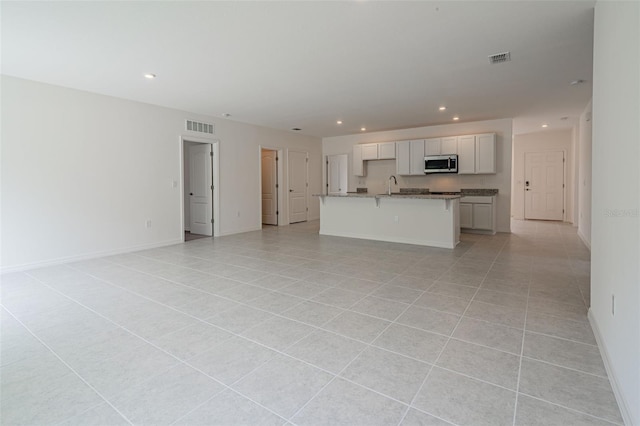 unfurnished living room featuring sink and light tile patterned floors