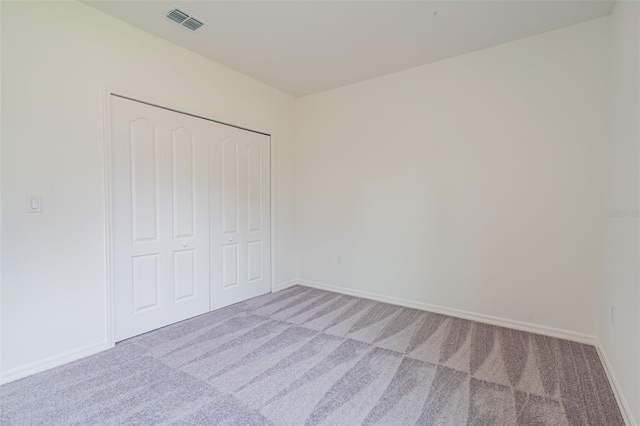 unfurnished bedroom with light colored carpet and a closet