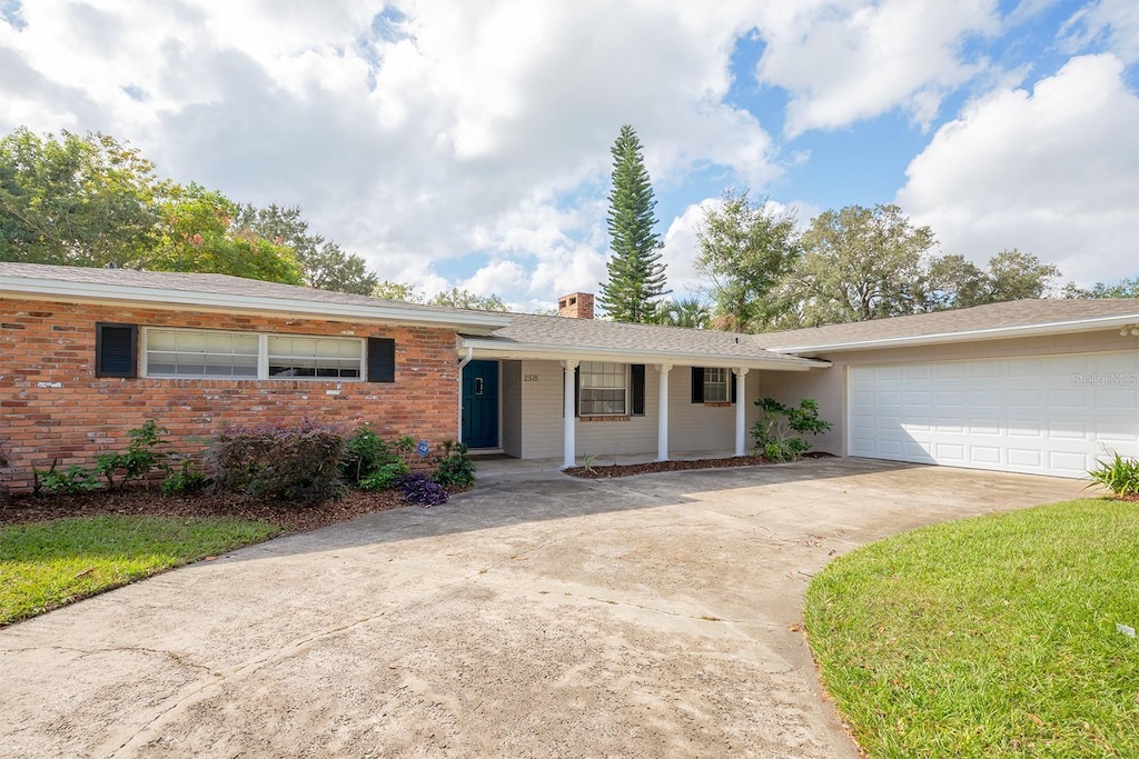 2518 Sweetwater Trl, Winter Park, FL 32789 - ranch-style home with driveway, a chimney, an attached garage, covered porch, and brick siding
