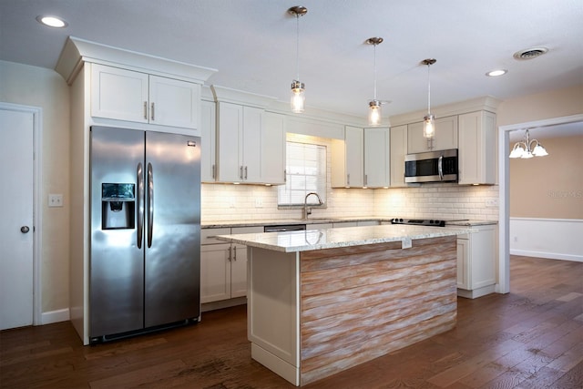 kitchen with stainless steel appliances, dark wood-type flooring, a center island, light stone countertops, and white cabinetry