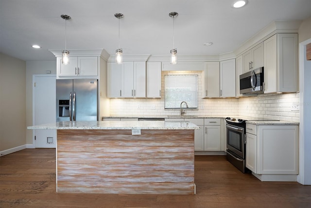 kitchen with light stone countertops, appliances with stainless steel finishes, decorative light fixtures, and a center island