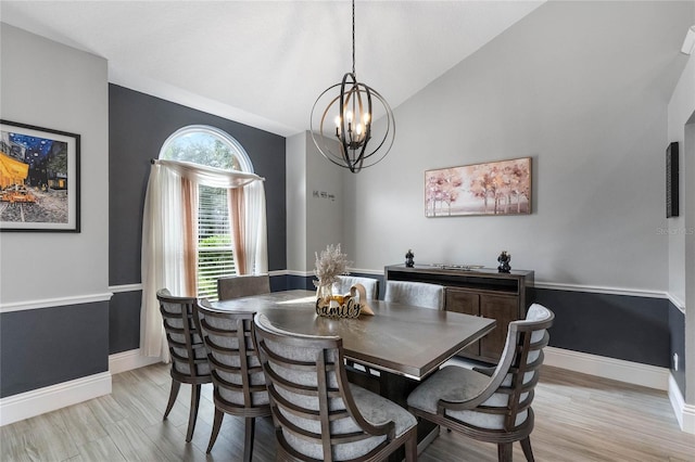 dining area featuring light wood-type flooring, a chandelier, and vaulted ceiling