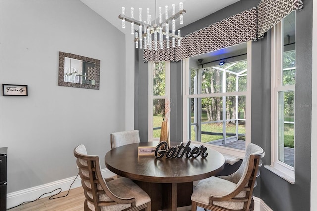 dining room with hardwood / wood-style floors, a healthy amount of sunlight, and an inviting chandelier