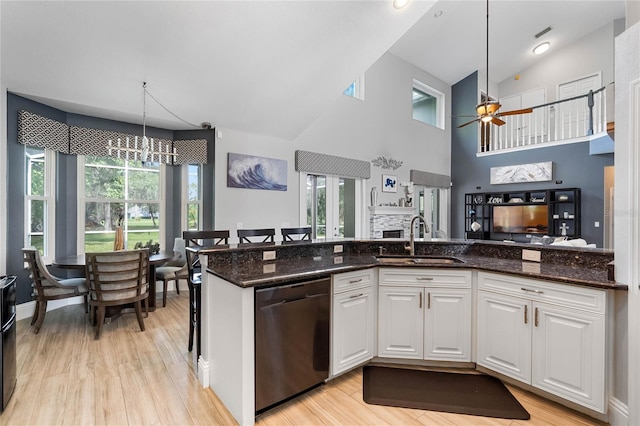 kitchen featuring dark stone counters, dishwasher, hanging light fixtures, sink, and white cabinetry