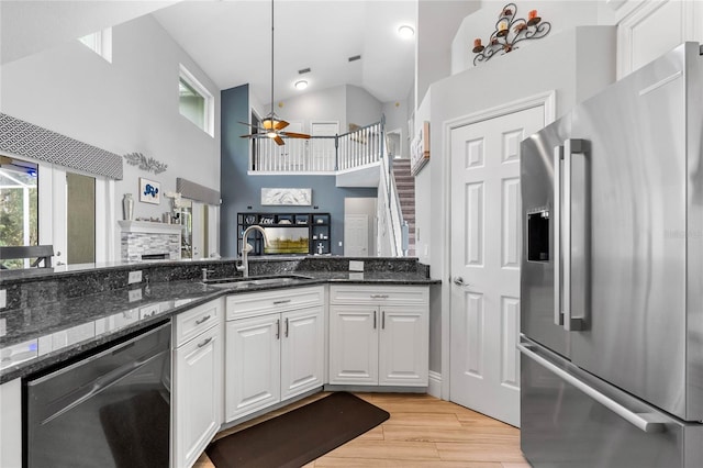 kitchen with light hardwood / wood-style floors, white cabinets, sink, high vaulted ceiling, and appliances with stainless steel finishes